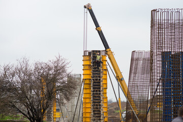 A worker climbs onto a reinforced concrete bridge support to dismantle the formwork