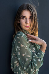  Calm beautiful young woman in elegant green dress near black wall
