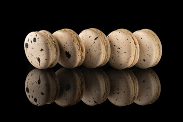 Group macaroons on black glass background with reflection
