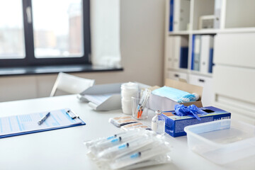 medicine, vaccination and healthcare concept - syringes, vaccine, protective medical gloves and plasters on table at hospital