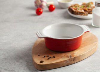 An empty red bowl on a wooden chopping board for soup, slices of bread with salted pork bacon or lard. Copy space.
