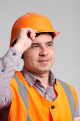 portrait of successful young construction worker in hard hat on grey studio background greeting