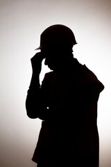 silhouette of tired builder bowed head in emotional stress on depressive isolated background, male unemployment concept