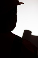 silhouette head of young construction worker in hard hat reading opened paper project in hands on isolated background, building industry concept