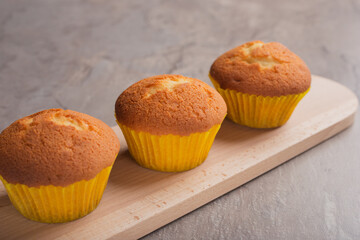 Freshly baked vanilla muffins on wooden board on dark stone table. Selective focus. Homemade food.