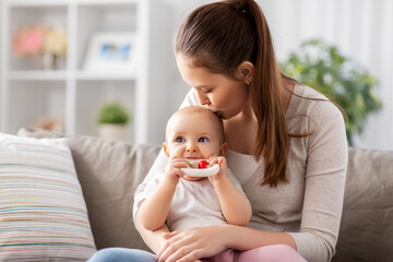 family, motherhood and people concept - happy smiling mother kissing little baby playing with...