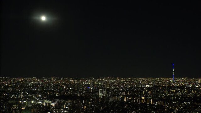 TOKYO, JAPAN : Aerial high angle view of CITYSCAPE of TOKYO at night. View of buildings around central downtown. Japanese city life and urban metropolis concept. Real time fixed shot. Full moon sky.