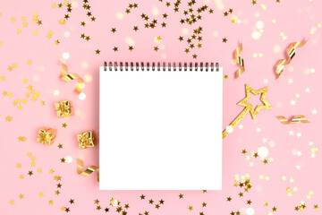 Notepad mockup with magic wand and gift boxes on a pink glittering background. Golden shiny confetti.