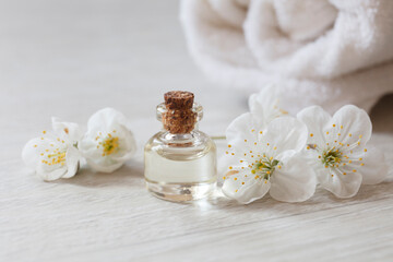 Obraz na płótnie Canvas apricot or cherry essential oil or perfume glass bottle with fresh flowers river pearls on wooden background, spa