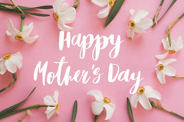 Happy mother's day. Happy mother's day text and white daffodils flowers frame composition on pink paper flat lay. Stylish floral greeting card. Handwritten lettering. Mothers day