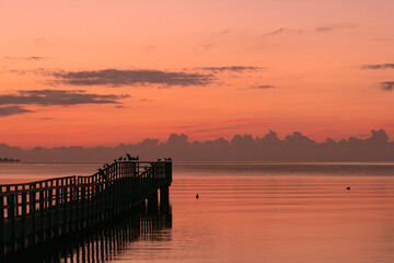 tranquil sea scene with pier and red sky, burial at sea