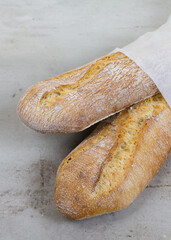 close up crusty baguettes, baked bread on grey stone table background. French bread. eco-friendly paper packaging. 