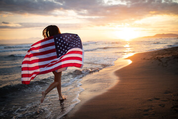 Cheerful happy woman outdoors on the beach holding USA flag having fun. - Powered by Adobe