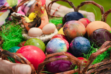 An elderly woman's hands holding a basket of colorful Easter eggs