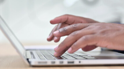 Side View of African Fingers Typing on Laptop