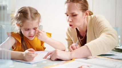 A schoolgirl does her homework and cries. mom sits next to her explains and is angry. complexities of correct and beautiful handwriting. there is no desire to learn. family and distance learning. 