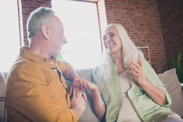 Obraz premium Portrait of nice cheerful couple sitting on sofa talking spending time having fun at modern loft industrial interior home indoor