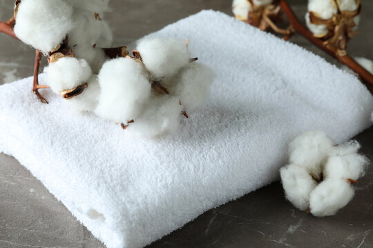 Cotton plant branches and towel on gray textured background