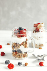 Healthy breakfast. Oatmeal granola with yogurt and fresh berries in glass jars on a wooden board. vertical photo. Place for text
