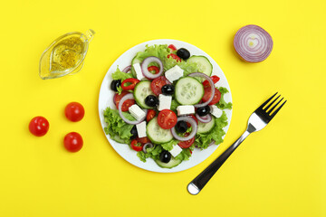 Concept of delicious food with Greek salad on yellow background