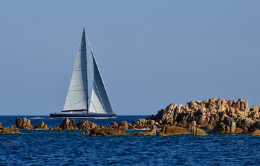 A modern sailboat sails along the coasts of Sardinia