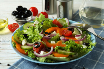 Concept of tasty eating with Greek salad on white wooden table
