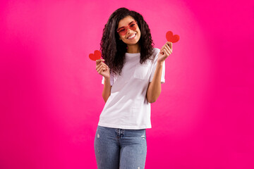 Photo of flirty millennial lady hold hearts wear spectacles t-shirt jeans isolated on pink color...