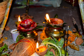 High angle close up shot of coconut, incense sticks, earthen lamps in Chhath Pooja prayer ceremony.
