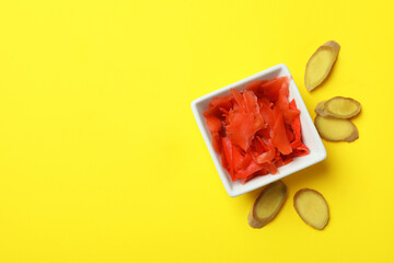 Bowl with red pickled ginger on yellow background