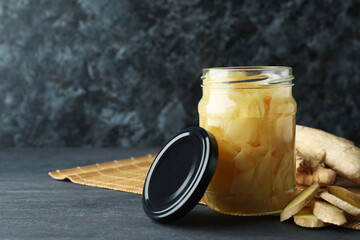 Jar of pickled ginger and ginger on dark wooden table