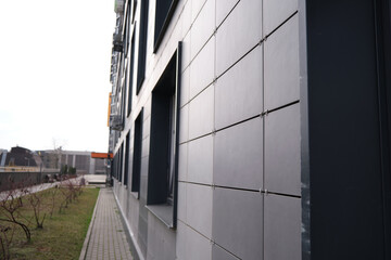 wall of office building made of metal plates with windows. Detail of modern residential building windows on ceramic ventilated facade.