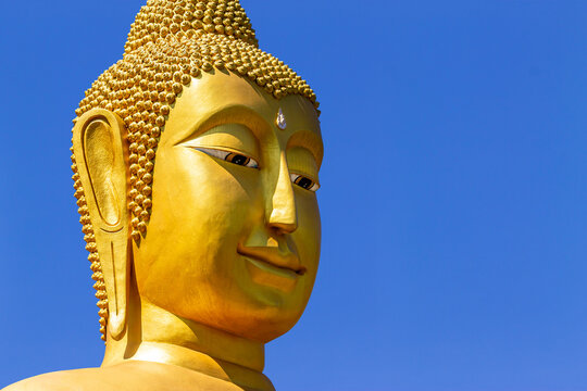 Big Buddha face, elegrant face of golden big buddha on blue sky background