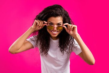 Portrait of attractive cheerful girl wearing touching specs looking at camera isolated over vivid pink fuchsia color background