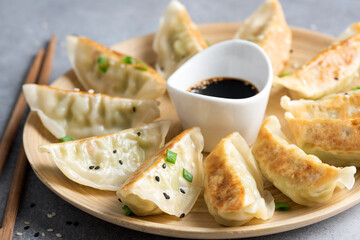 Gyoza or jiaozi fried stuffed dumplings on a bamboo plate, closeup view