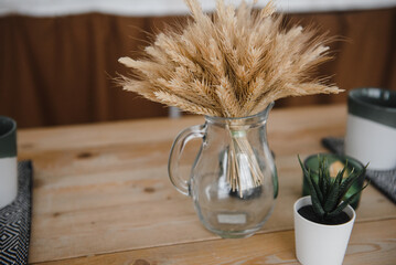 ears of corn in a glass transparent vase on a wooden table in the village