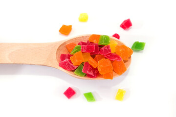 colored candied fruits in a wooden spoon on a white
