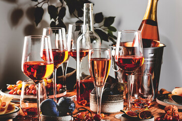 Pink rose wine glasses and bottles on table served for summer festive dinner party with different kinds of appetizers