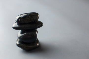 Black massage stones stacked on gray paper background