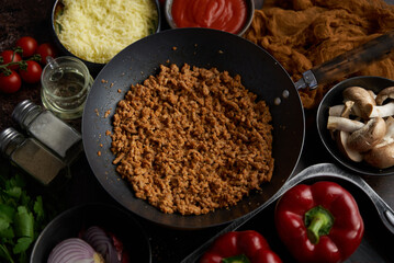 Ingredients on a table prepared for stuffing peppers. Red bell peppers, minced meat, cheese