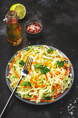 Coleslow cabbage salad with carrot on grey kitchen table. Top view, copy space
