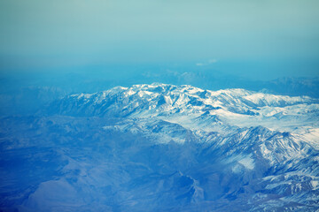 Fototapeta na wymiar View of the snow-covered mountains from the plane