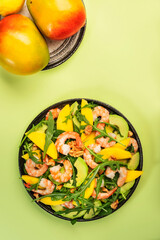 Fresh Seafood Salad with Shrimps, Mango and Avocado, Walnut, Spinach and Arugula. Healthy food. Top view, green background