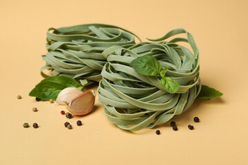 Uncooked green pasta and spices on beige background