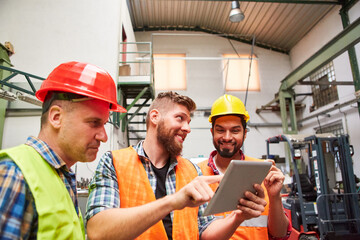Group of workers in factory with order on tablet computer