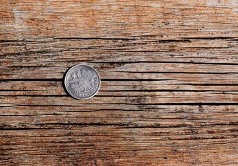 an old coin  on a wood colored background