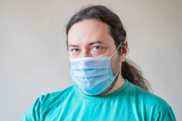 An adult male in a protective medical mask looks forward. Close-up of a man looking at the camera
