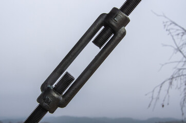Closeup-Turnbuckles that pull the rope in front of grey sky, Copy Space