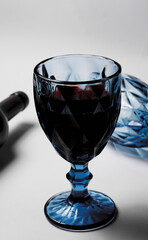 A bottle of red wine with a blue wine glass, on a white background