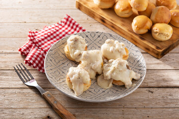 Traditional American biscuits and gravy for breakfast on wooden table	