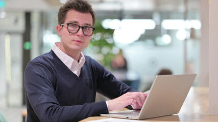 Young Businessman with Laptop Looking at Camera